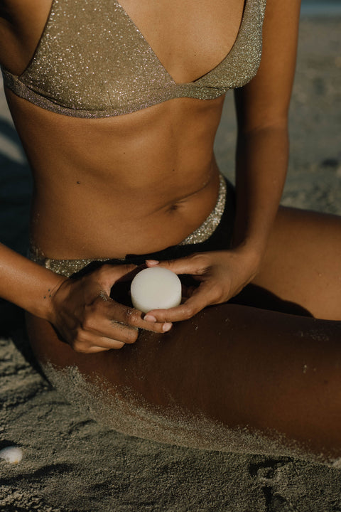 woman sitting on beach holding a conditioner bar