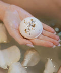 bath and shower bomb in hand over tub