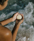 shampoo bar in hands over ocean